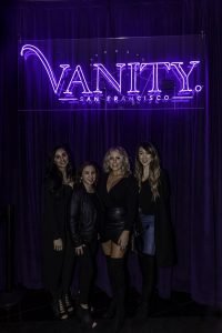 4 Girls smiling under vanity sign.