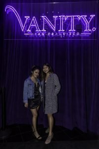Two Girls Smiling under sign