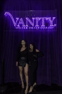 Two Girls Posing under Vanity Sign